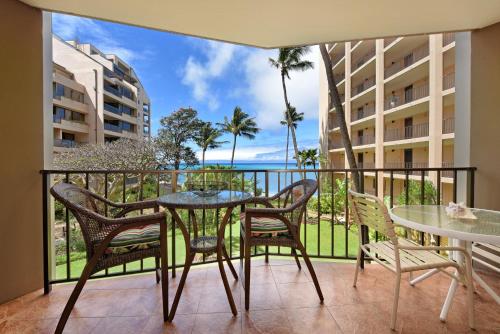 a balcony with a table and chairs and a view of the ocean at Valley Isle 302 in Kahana