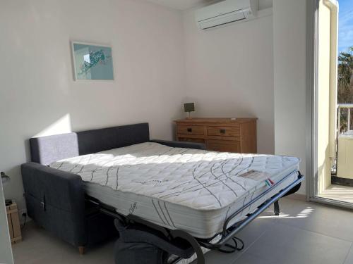 un lit assis dans une pièce avec une fenêtre dans l'établissement Studio rénové près des Thermes avec balcon et climatisation - FR-1-553-252, à Balaruc-les-Bains