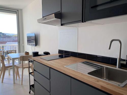 - une cuisine avec un évier et un comptoir avec une table dans l'établissement Studio rénové près des Thermes avec balcon et climatisation - FR-1-553-252, à Balaruc-les-Bains
