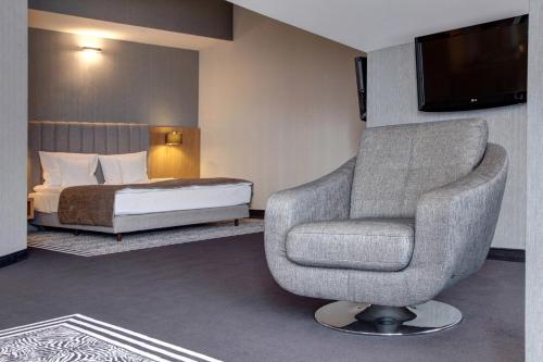a room with a chair and a bed and a television at Hotel & Medi-Spa Biały Kamień in Świeradów-Zdrój