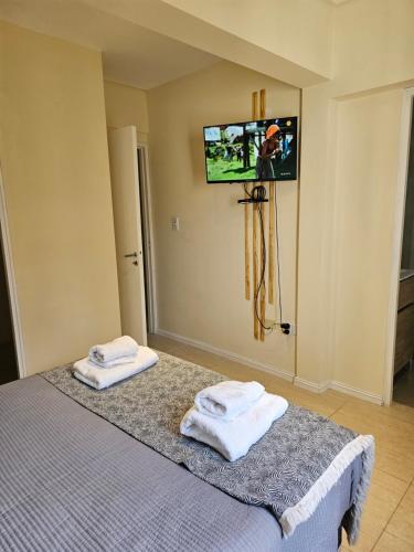 Departamento Azcuénaga Sur في غوايمالين: غرفة نوم مع سرير وتلفزيون على الحائط