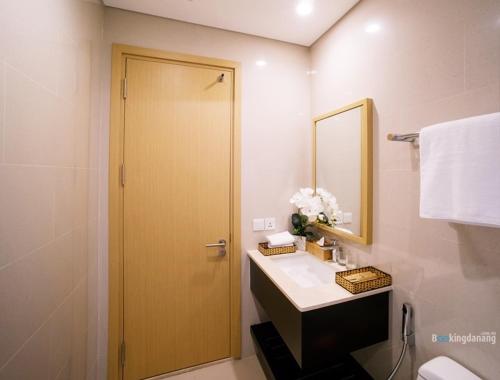 a bathroom with a sink and a door with a mirror at Ocean Apartment Two Bedrooms in Danang