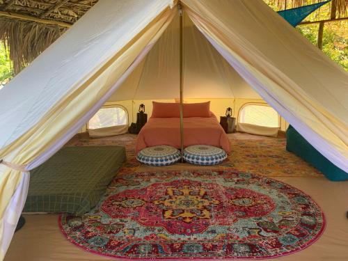 a bedroom in a tent with a bed and a rug at Humble Boy retreat Glamping yurt in Negril