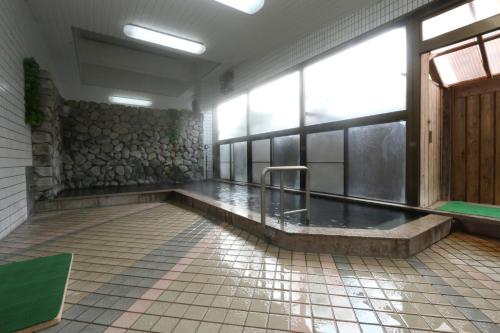 une salle de bains avec un bain à remous dans un bâtiment dans l'établissement 旅館　松乃湯, à Kutami