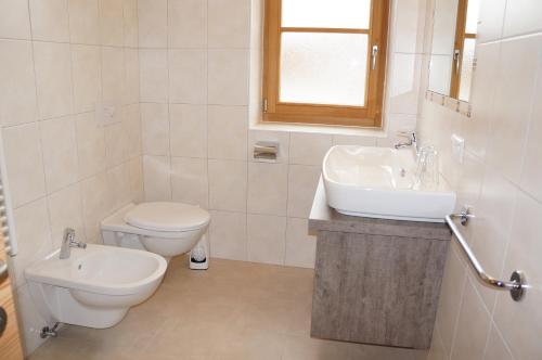 a white bathroom with a toilet and a sink at Chi Plans in Antermoia