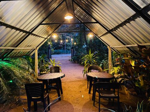 a patio with tables and chairs in a greenhouse at Forest Villa in Sigiriya