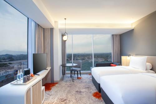 um quarto de hotel com duas camas e uma televisão em HARRIS Hotel & Convention Cibinong City Mall Bogor em Bogor
