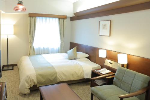 a hotel room with a bed and a chair at Kurashiki Kokusai Hotel in Kurashiki