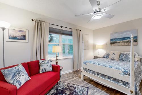 1 dormitorio con 1 cama y 1 sofá rojo en 4628 Whimbrel Lane, en Fernandina Beach