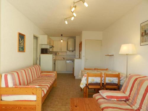 un salon avec un canapé et des chaises et une cuisine dans l'établissement Appartement 2 Pièces au Lavandou avec Terrasse, Wi-Fi et Parking Privé à 5min de la Plage - FR-1-251-710, au Lavandou