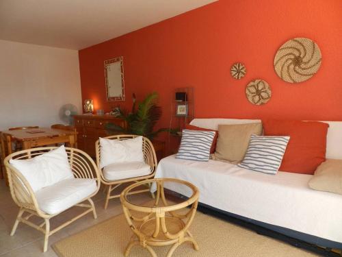 - une chambre avec 2 lits, des chaises et un mur orange dans l'établissement Appartement Confort 2 P. avec Terrasse, Plage et Commerces à 200 m - Parking Privé Inclus - FR-1-251-715, à Bormes-les-Mimosas