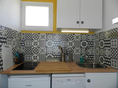 - une cuisine avec un évier et un mur en carrelage dans l'établissement Appartement Confort 2 P. avec Terrasse, Plage et Commerces à 200 m - Parking Privé Inclus - FR-1-251-715, à Bormes-les-Mimosas