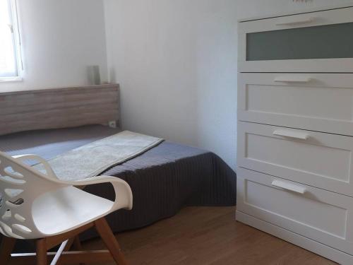 um quarto com uma cómoda e uma cadeira ao lado de uma cama em Appartement Bormes-les-Mimosas, 2 pièces, 4 personnes - FR-1-251-735 em Bormes-les-Mimosas