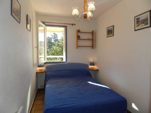 Un pequeño dormitorio con una cama azul y una ventana en Appartement Bormes-les-Mimosas, 2 pièces, 4 personnes - FR-1-251-724, en Bormes-les-Mimosas