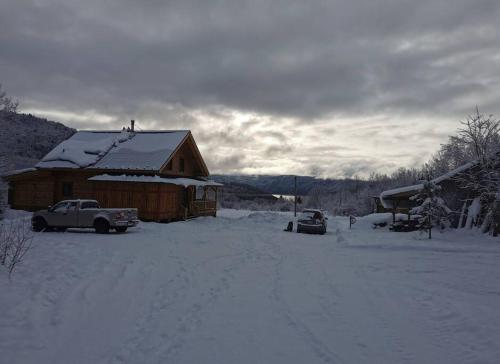 a snow covered house with a truck parked in front of it at Gîte de l'herboriste in Sainte-Rose-du-Nord