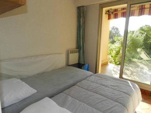 une chambre avec deux lits et une grande fenêtre dans l'établissement Charmant T2 avec grande terrasse à 250m de la plage - 4 couchages, garage privé, ménage inclus - FR-1-251-741, à Bormes-les-Mimosas