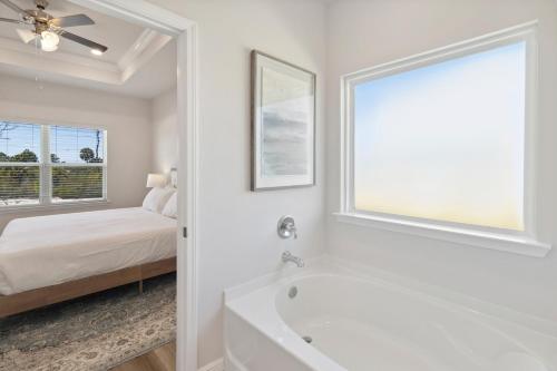 Saint Joe BeachにあるWindmark - Jasmine by the Beachの白いバスルーム(ベッド1台、バスタブ付)