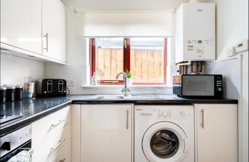a white kitchen with a washing machine and a sink at Ochil View Holiday Let in Tullibody