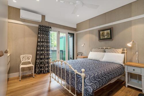 a bedroom with a bed and a chair and a window at Belongil Laneway in Byron Bay