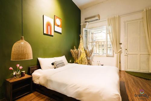 - une chambre avec un lit blanc et un mur vert dans l'établissement OH Trendy APARTMENT TT, à Hanoï