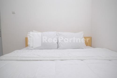 uma cama branca com almofadas brancas em River House Mitra RedDoorz em Jatingaleh