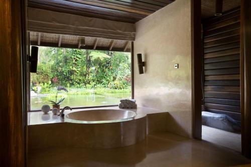 a bathroom with a tub and a large window at Kamaniiya River Villa Sayan - Ubud in Ubud