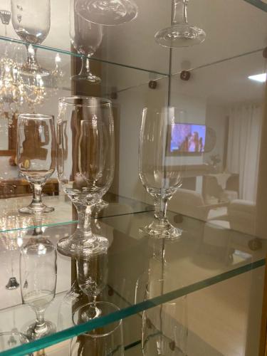 une étagère en verre avec plusieurs verres à vin dans l'établissement LUXUOSO APT ALMERIS PECCIN no Centro de GRAMADO, à Gramado