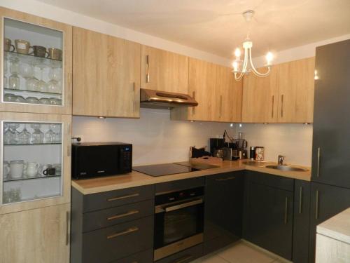 La cuisine est équipée de placards en bois, d'un évier et d'un four micro-ondes. dans l'établissement Appartement Moderne avec Terrasse, Parking et Proximité Plage à Bormes les Mimosas - FR-1-251-745, à Bormes-les-Mimosas