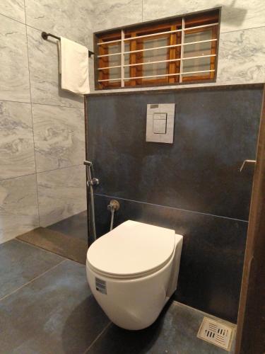 a bathroom with a white toilet in a room at Ananda Holiday Home in Ambalavayal