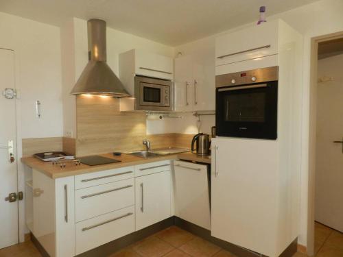 eine Küche mit weißen Schränken, einer Spüle und einer Mikrowelle in der Unterkunft Appartement La Londe-les-Maures, 2 pièces, 6 personnes - FR-1-251-750 in La Londe-les-Maures