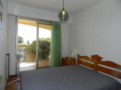 une chambre avec un lit et une porte coulissante en verre dans l'établissement Appartement T2 cosy avec jardin, proche plage et commerces – Bormes-les-Mimosas - FR-1-251-756, à Bormes-les-Mimosas