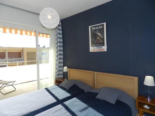 une chambre avec un lit avec un mur bleu dans l'établissement Appartement climatisé, terrasse, parking privé, à 150m de la plage - Bormes-les-Mimosas - FR-1-251-759, à Bormes-les-Mimosas