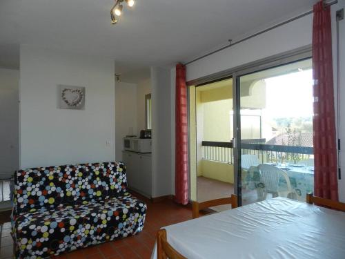 - une chambre avec un lit, un canapé et un balcon dans l'établissement Charmant T2 avec terrasse et parking au calme, Le Lavandou - FR-1-251-766, au Lavandou