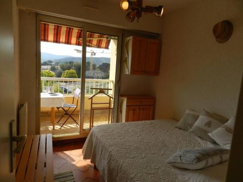 une chambre avec un lit et une vue sur un balcon dans l'établissement Charmant appart T2 avec terrasse, proche plage et commerces, garage privé, Bormes-les-Mimosas - FR-1-251-755, à Bormes-les-Mimosas