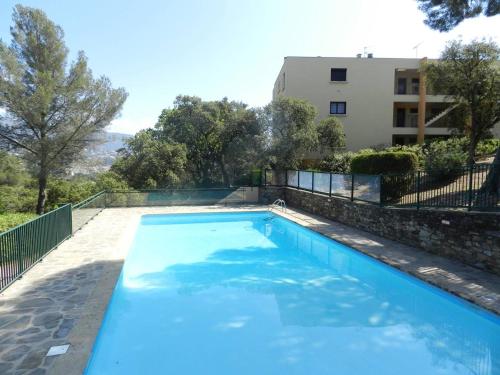 une grande piscine bleue à côté d'un immeuble dans l'établissement Appartement 3 pièces avec piscine, parking et animaux admis - FR-1-251-757, au Lavandou
