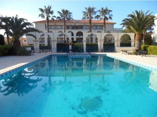 une piscine devant un immeuble avec des palmiers dans l'établissement Appartement T2 avec Cabine, Piscine, Parking Privé - Proche Plage et Commerces, Le Lavandou - FR-1-251-774, au Lavandou