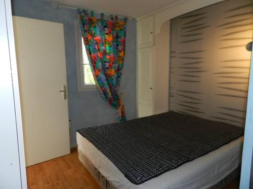 ein Schlafzimmer mit einem Bett und einem Fenster mit einem Vorhang in der Unterkunft Appartement Le Lavandou, 2 pièces, 4 personnes - FR-1-251-769 in Le Lavandou