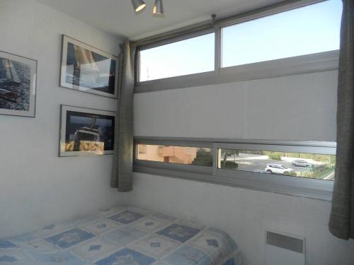 ein Schlafzimmer mit zwei Fenstern und einem Bett darin in der Unterkunft Appartement Bormes-les-Mimosas, 3 pièces, 6 personnes - FR-1-251-771 in Bormes-les-Mimosas