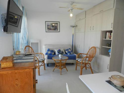 un salon avec un canapé et une table avec des chaises dans l'établissement Studio avec terrasse, parking privatif et proche plage - Le Lavandou - FR-1-251-772, au Lavandou