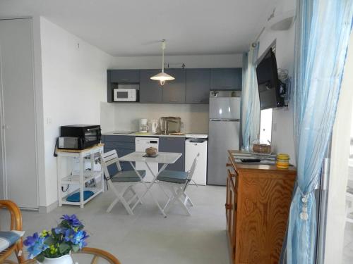 La cuisine est équipée d'une table, de chaises et d'un réfrigérateur. dans l'établissement Appartement Le Lavandou, 1 pièce, 2 personnes - FR-1-251-772, au Lavandou