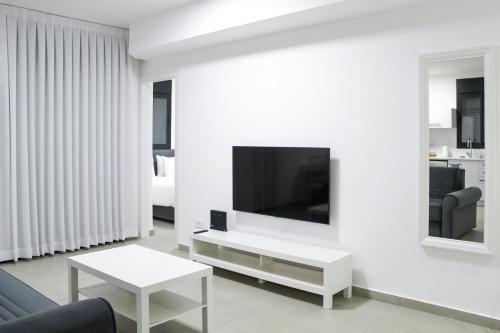 een woonkamer met een tv aan een witte muur bij Family Apartment #9 By Hashdera Eilat in Eilat