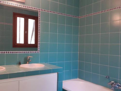 La salle de bains est pourvue de carrelage bleu, d'un lavabo et d'une baignoire. dans l'établissement Maison 3 pièces avec piscine privée à Bormes-les-Mimosas - FR-1-251-777, à Bormes-les-Mimosas