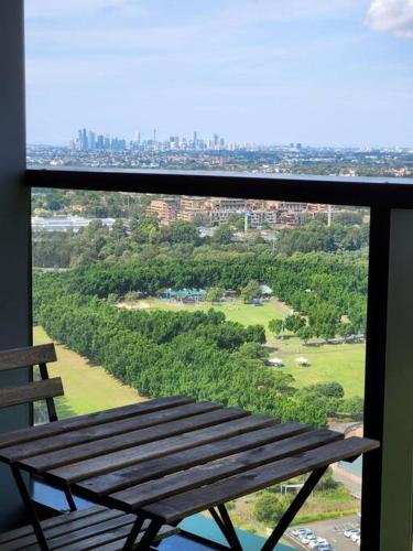 a wooden bench sitting on top of a balcony at Modern Apartment with City View at Sydney Olympic Park in Sydney