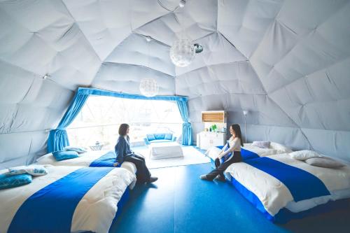 two women sitting on beds in a white room at Kanonji City - Camp - Vacation STAY 42267v in Kanonji