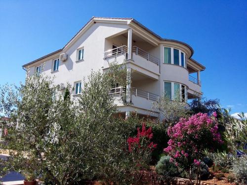 a white building with a balcony and some trees at Apartments Kovacic in Malinska