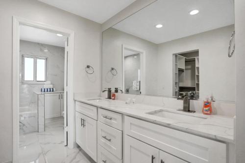 a white bathroom with two sinks and a shower at The Marvelous 24 in Flagler Beach