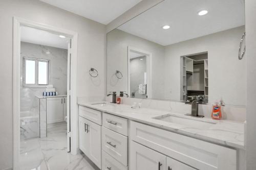 a white bathroom with two sinks and a shower at Immaculate, modern stay steps to beach with amazing ocean views in Painters Hill