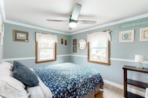 a bedroom with a bed and two windows at Shoreline Serenade in Belmont