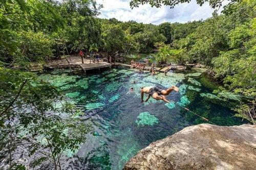 a man jumping into a pool in a river at Akumal Skies Private Terrace W Jacuzzi W Sea Views Walk To Beach in Akumal