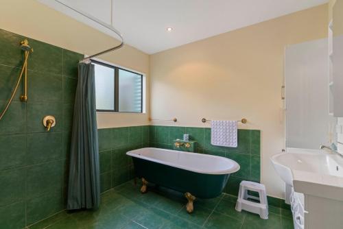 a green bathroom with a tub and a sink at Modern Barn Style - Taupo Holiday Home in Kinloch